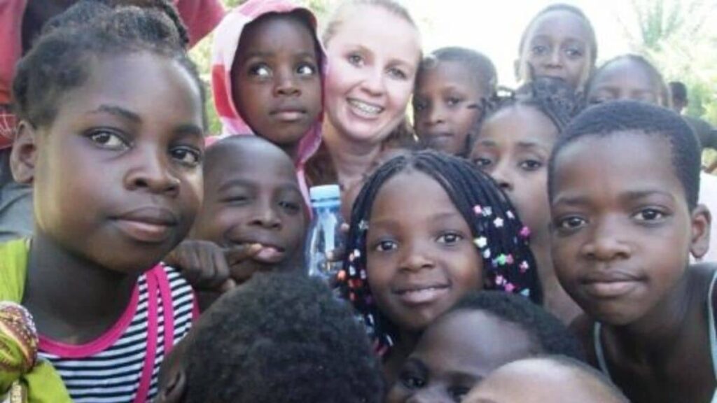 Voluntária Juliana do Instituto Alce abraça crianças em Moçambique, símbolo de missão humanitária e inclusão social na África.