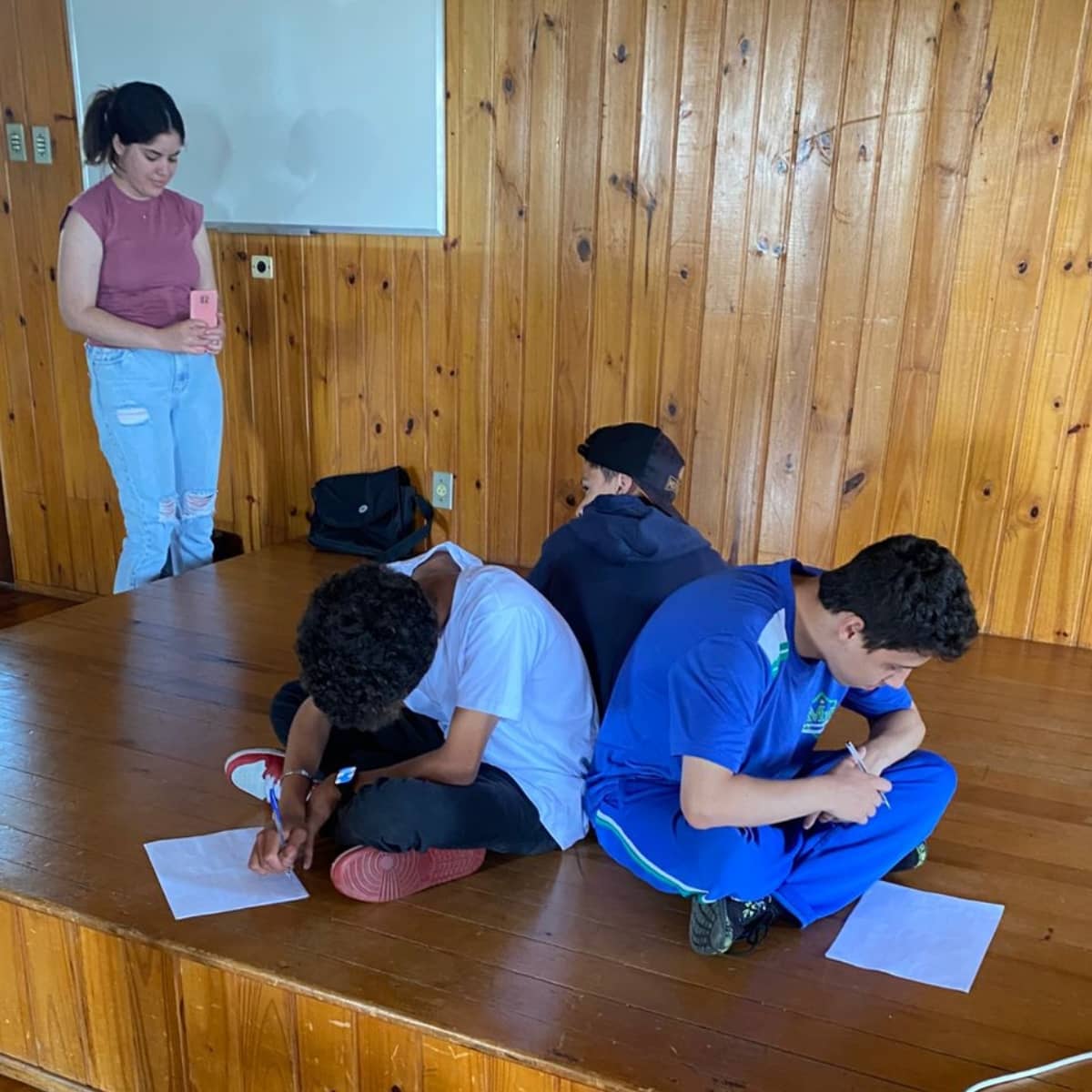 Três jovens refletindo sobre seus Planos de Desenvolvimento Individuais após orientação de Maria Estela no programa de mentoria do Instituto Alce