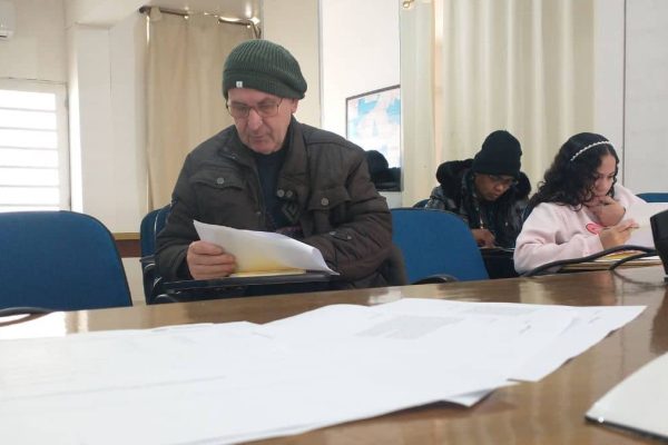 Aluno idoso concentrado em leitura e resolução de questões no preparatório ENCCEJA do Instituto Alce para escolaridade na adultez.