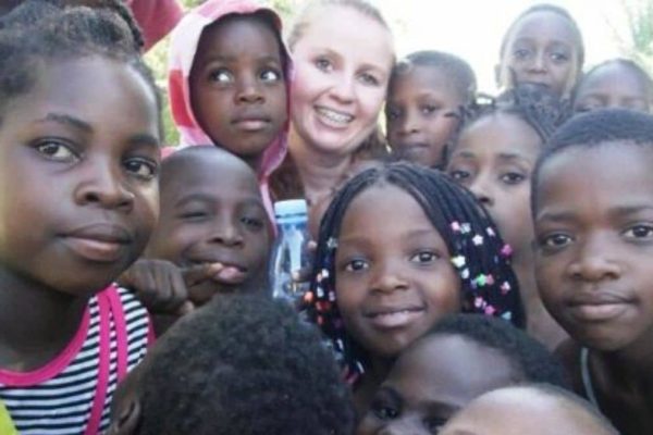 Voluntária Juliana do Instituto Alce abraça crianças em Moçambique, símbolo de missão humanitária e inclusão social na África.
