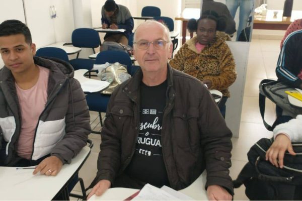 Alunos adultos, incluindo idoso e refugiados haitianos e venezuelanos, em aula de escolaridade na adultez no Instituto Alce.